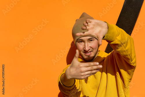 A stylish guy in a yellow hoodie makes a gesture with his hands © Cavan