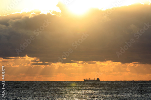 commercial cargo ship in the sun and dark clouds