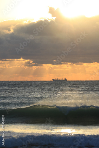 commercial cargo ship sailing in the sun and dark clouds