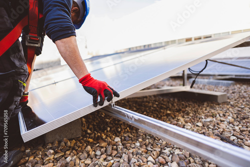 Detail shot of a solar panel installer placing the solar panel on the roof photo