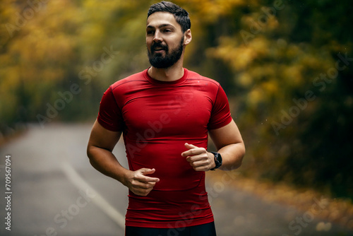 Portrait of a sportsman running in nature on a rainy weather.