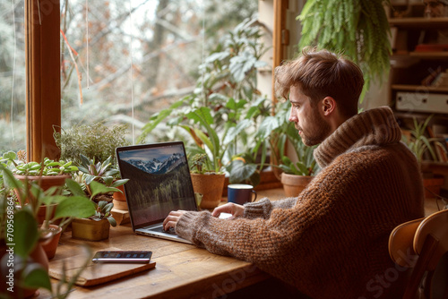 Man working from home at his plant lovers desk with a forest view in his cabin