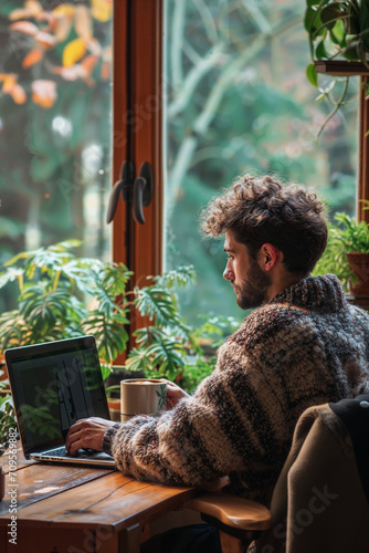 Man working from home at his plant lovers desk with a forest view in his cabin