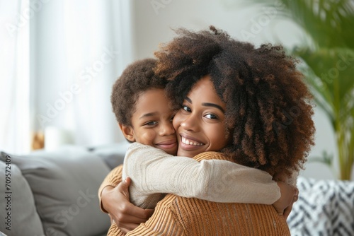 In a bright and cozy living room, an afro mother expresses love, hugging her joyful child, creating a heartwarming moment of connection and happiness. photo