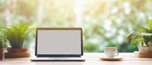 Laptop with blank screen and coffee cup on wooden table in coffee shop .