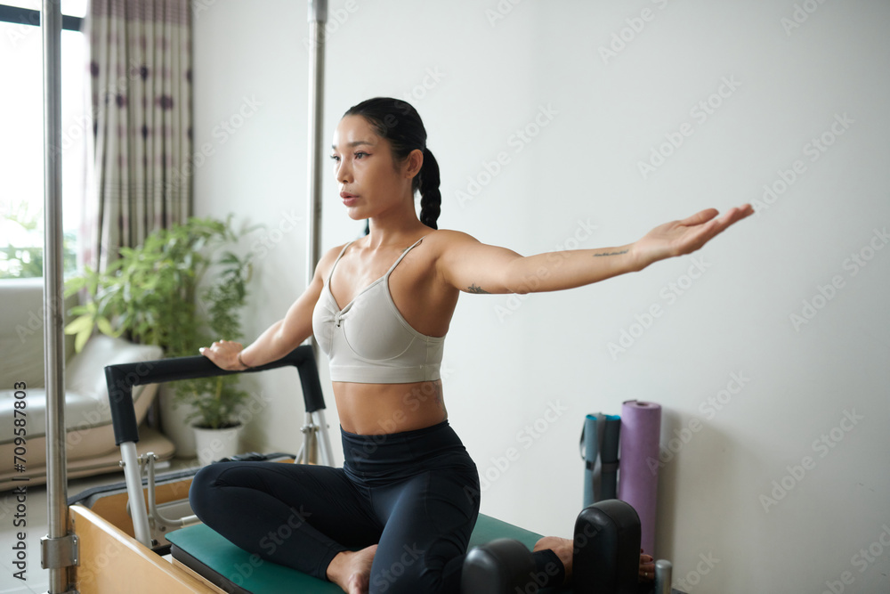 Fit young woman doing side bend when exercising in special machine Fit young woman doing side bend when exercising in special machine