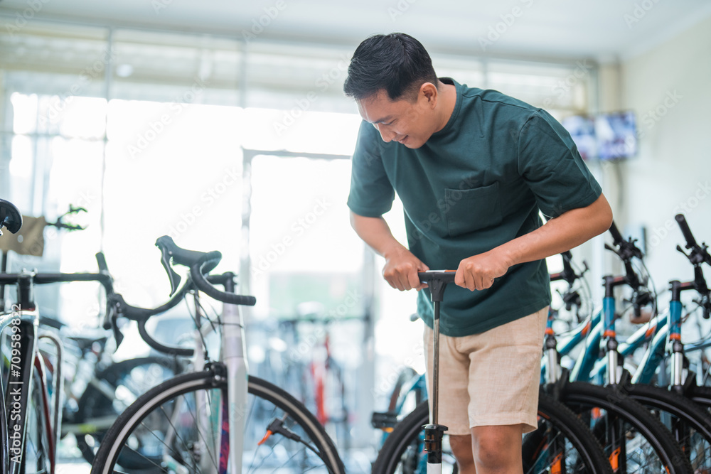 young man smiles while pumping up racing bike tires at a bike shop young man smiles while pumping up racing bike tires at a bike shop