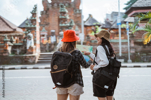 two local female tourists using a map in front of a religious temple