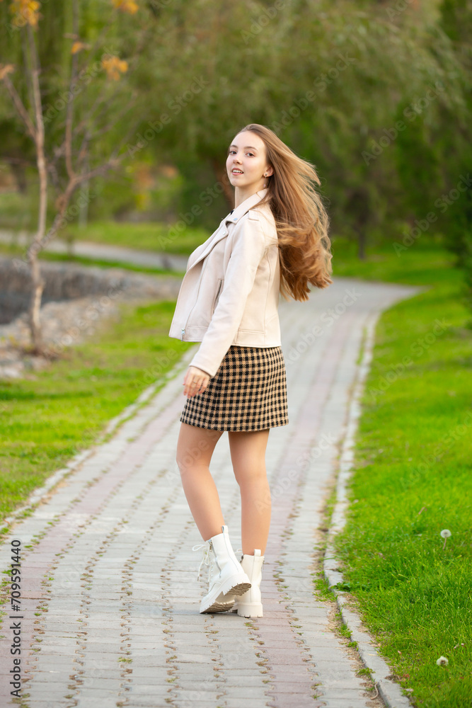 A young smiling girl walking in an autumn park in a good mood. Teenage girl, portrait against a background of nature. Fashion style trend. A young smiling girl walking in an autumn park in a good mood. Teenage girl, portrait against a background of nature. Fashion style trend.
