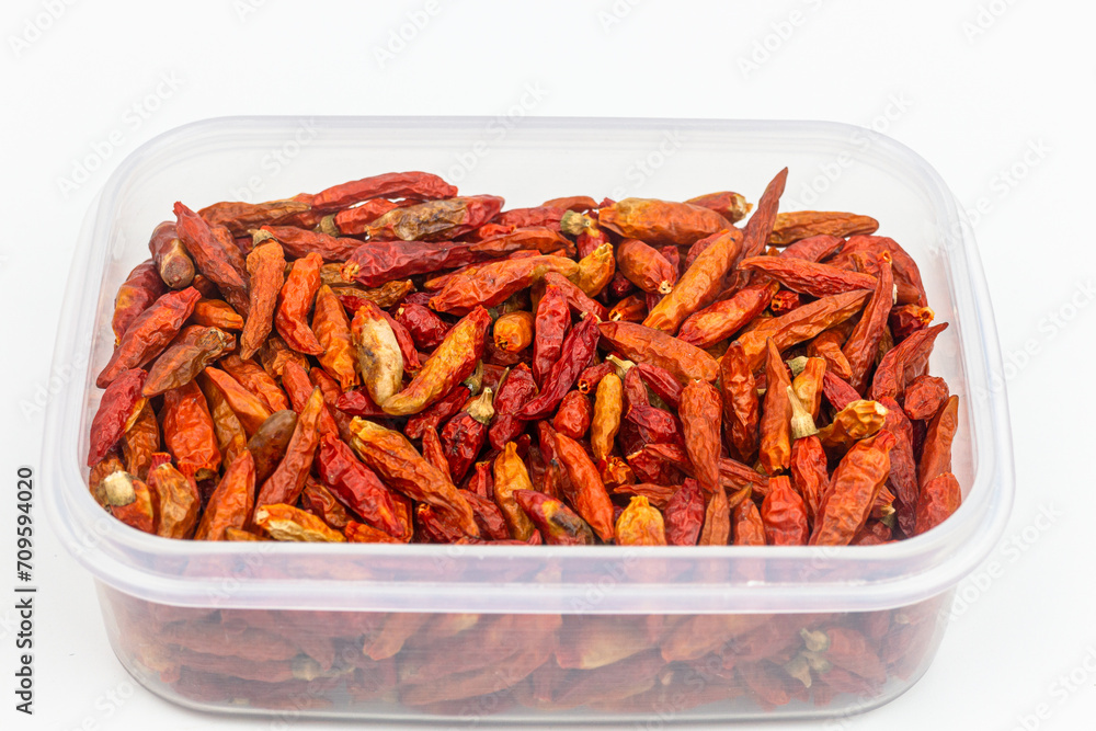 Dried red chilli pepper in plastic box on white background. Dried red chilli pepper in plastic box on white background.