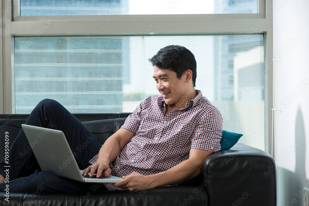 Asian man at home using a laptop. Asian man at home using a laptop.