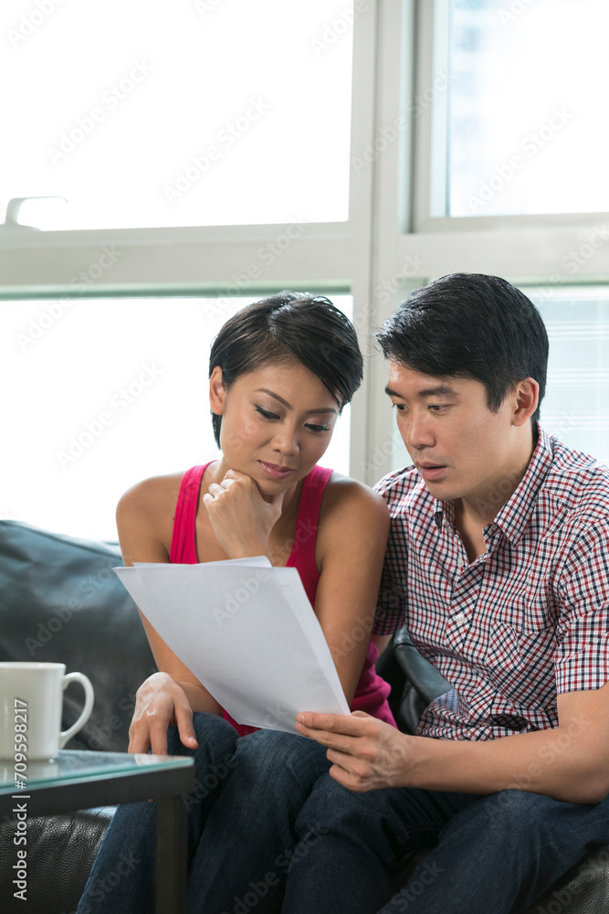 Serious Asian couple reading a financial bill Serious Asian couple reading a financial bill
