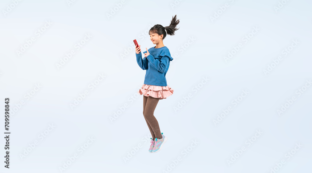 スマホを見ながらジャンプする女の子（切り抜き背景透過PNGも販売しております。作成者リンクから「PNG」で検索してください）