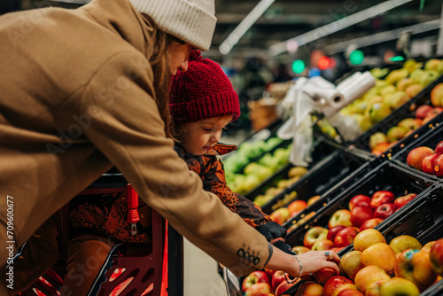 Young woman and son buying apples at supermarket photo