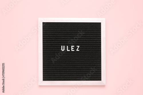 The word ulez on black letter board over isolated beige background photo