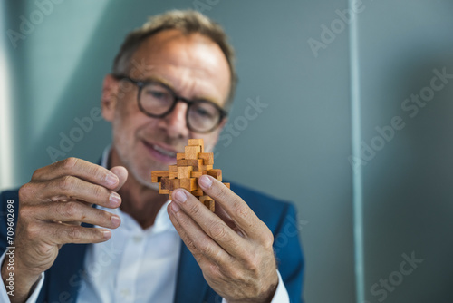 Smiling businessman holding wooden toy blocks in office photo