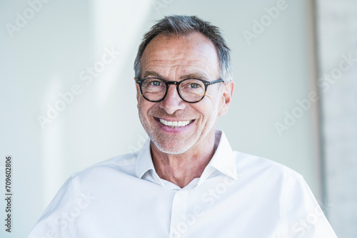 Happy senior businessman in front of white wall photo