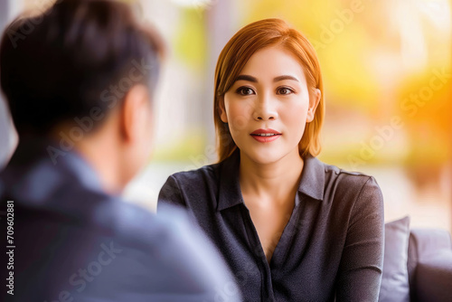 Wallpaper Mural Professional Asian businesswoman listening attentively to a colleague during a serious discussion in a bright corporate setting. Torontodigital.ca