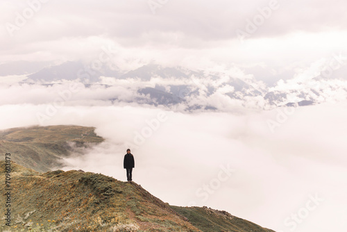 Woman standing on Mestia mountain cliff near clouds photo