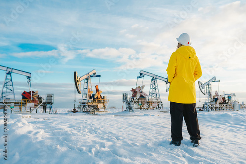 Young engineer standing at oil production field in winter photo