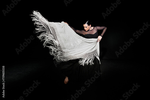 Young flamenco dancer performing with shawl against black background photo