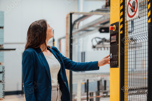 Businesswoman touching push button on control panel in industry photo