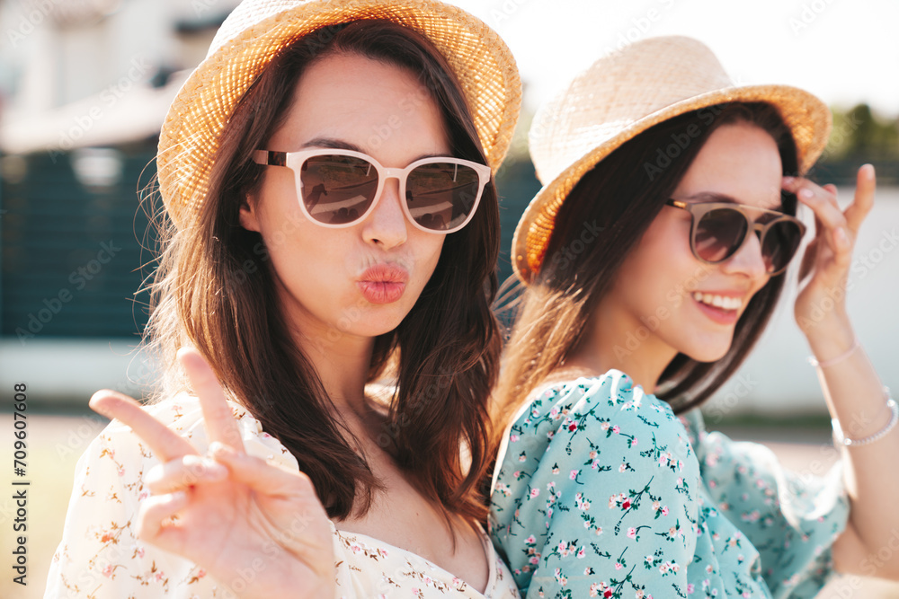 Two young beautiful smiling hipster female in trendy summer dresses clothes. Sexy carefree women posing in the street. Positive models having fun at sunny day. Going crazy. In sunglasses Two young beautiful smiling hipster female in trendy summer dresses clothes. Sexy carefree women posing in the street. Positive models having fun at sunny day. Going crazy. In sunglasses