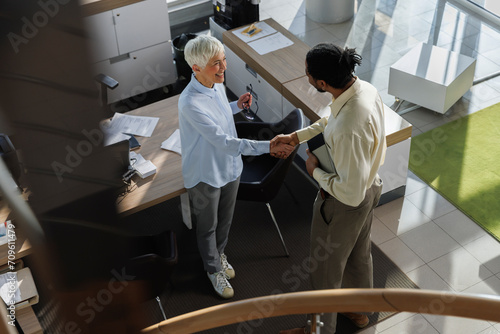 Smiling businesswoman doing handshake with candidate at office