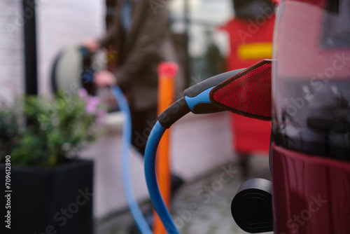 Electric plug connected to car charging at station photo