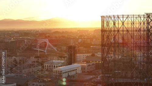 Alba sul Gazometro del quartiere post industriale Ostiense a Roma, Italia.
Veduta aerea con drone dei raggi del sole che passano attraverso la vecchia struttura del Gasometro. photo