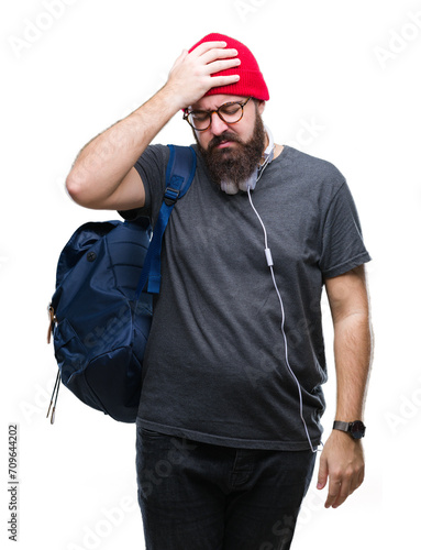 Young hipster man wearing red wool cap and backpack over isolated background suffering from headache desperate and stressed because pain and migraine. Hands on head.