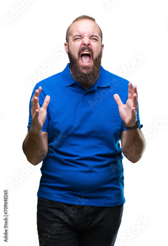 Young caucasian hipster man wearing blue shirt over isolated background crazy and mad shouting and yelling with aggressive expression and arms raised. Frustration concept.