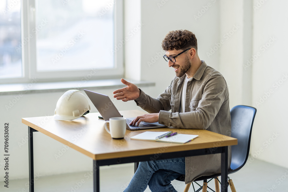 Successful young man looking on laptop video call while working at home office