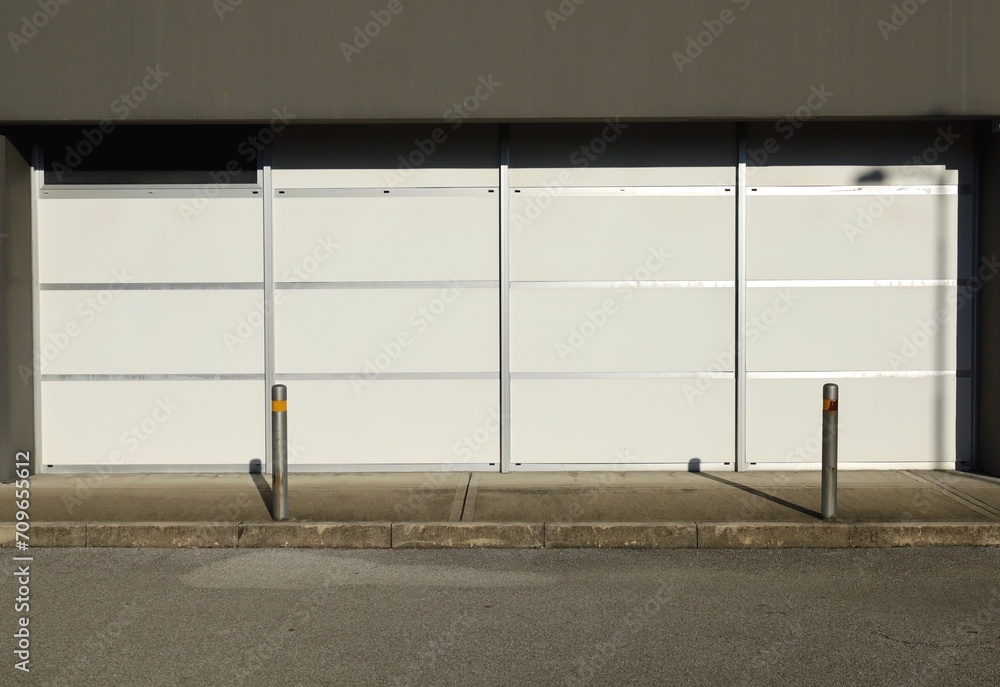 Office white glazed windows on aluminium frame at floor level. Concrete sidewalk with fixed bollards and street in front. Background for copy space. Office white glazed windows on aluminium frame at floor level. Concrete sidewalk with fixed bollards and street in front. Background for copy space.