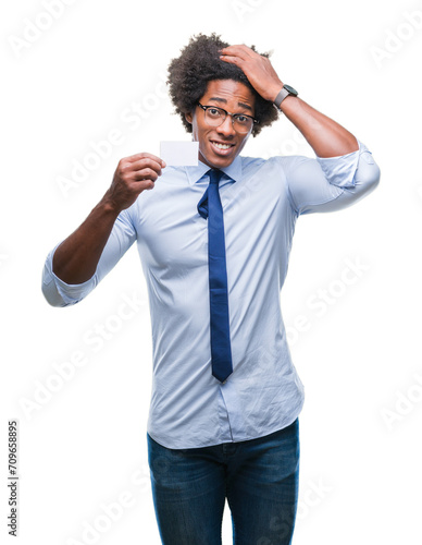 Afro american man holding visit card over isolated background stressed with hand on head, shocked with shame and surprise face, angry and frustrated. Fear and upset for mistake.