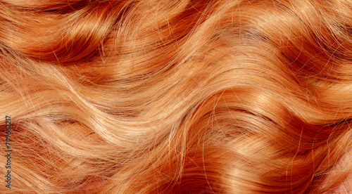 Red hair close-up as a background. Women's long orange hair. Beautifully styled wavy shiny curls. Hair coloring bright shades. Hairdressing procedures, extension. photo