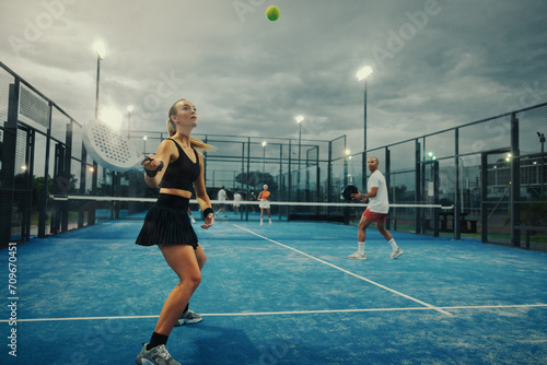 Evening padel championship: Young female athlete competing in doubles match