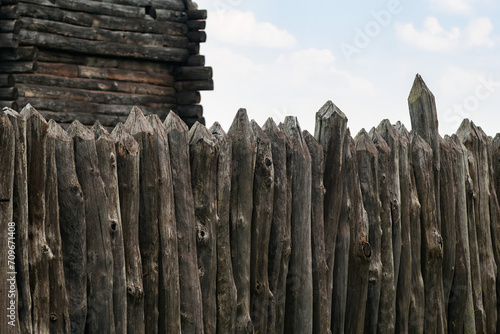 Fortification fence made of pointed logs against the background