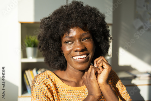Happy thoughtful woman resting chin on hands at home