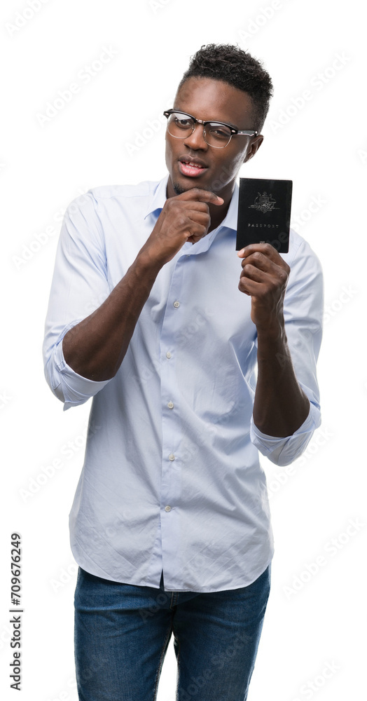Young african american man holding australian passport serious face thinking about question, very confused idea Young african american man holding australian passport serious face thinking about question, very confused idea