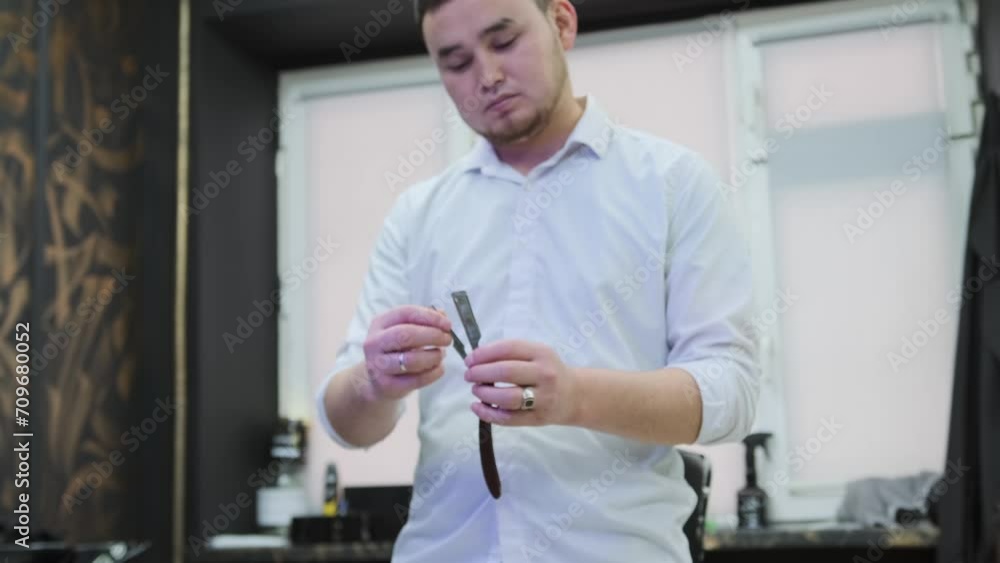 The barrier holds a straight razor in its hands and pushes it apart, demonstrating its blades in a barbershop. Close-up, front view The barrier holds a straight razor in its hands and pushes it apart, demonstrating its blades in a barbershop. Close-up, front view
