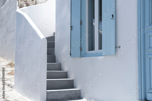 greek traditional island house with blue wooden windows and doors, whitewashed cement concrete streets and stairs