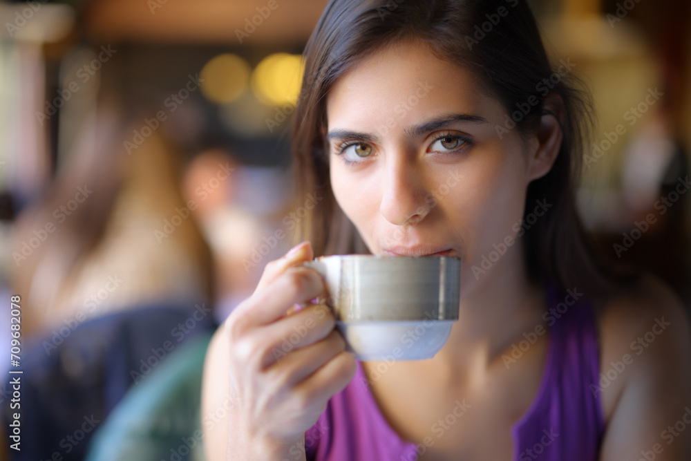 Woman drinking coffee looking at you in a shop Woman drinking coffee looking at you in a shop