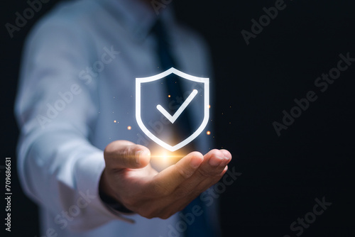 Businessman showing virtual sign of shield with a check mark for insurance concept.