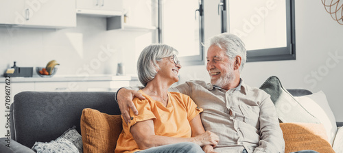 Happy laughing older married couple talking, laughing, standing in home interior together, hugging with love, enjoying close relationships, trust, support, care, feeling joy, tenderness. photo