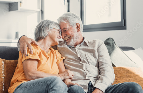 Happy laughing older married couple talking, laughing, standing in home interior together, hugging with love, enjoying close relationships, trust, support, care, feeling joy, tenderness.