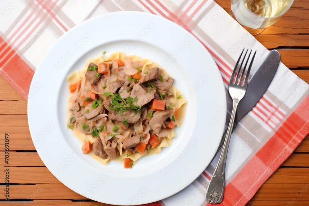 plated beef stroganoff with fork and knife on either side, napkin underneath