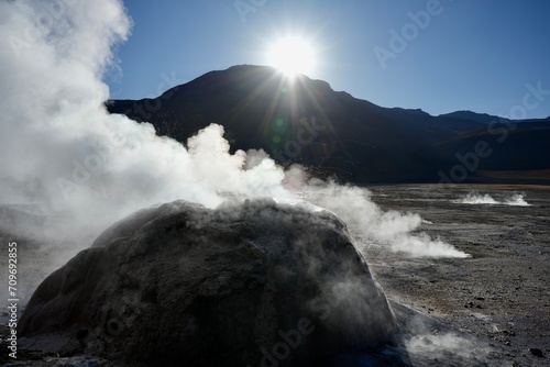 Steam rising from a bolder geyser at The Geysers Del Tatio, Antofagasta, Chile, with blue skies behind. 