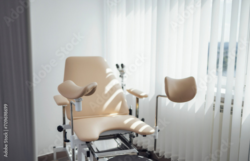 Empty gynecological chair. Modern light color office of the gynecologist in professional medical clinic. Sunny day. Pregnancy planning and female health care concept. © Dasha Petrenko