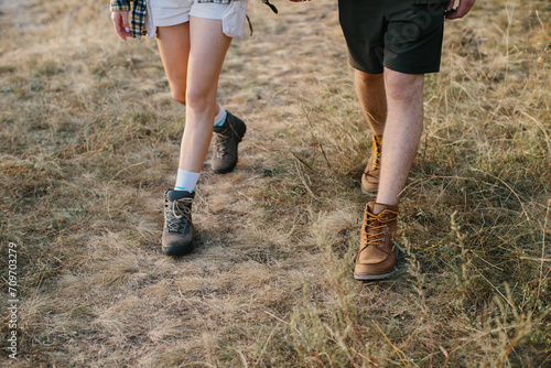A guy and a girl are walking together holding hands during a hike in the mountains. Legs close-up.